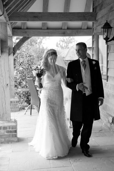 Black and white picture of a bride being led by the arm by Fiona Kelly Photography