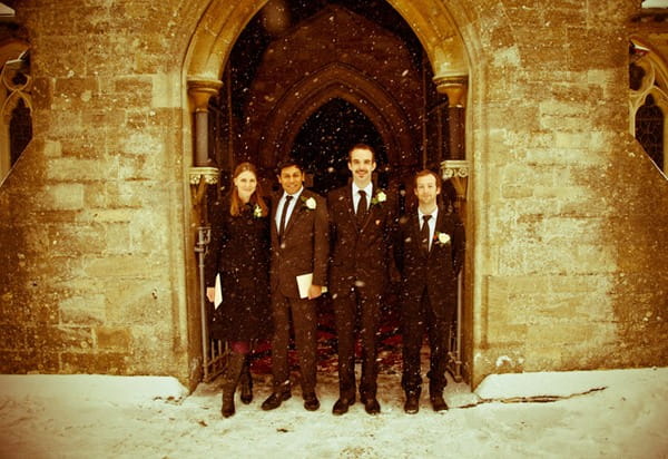 Picture of a bridal party standing in the doorway of a church in the snow by Anneli Marinovich Photography