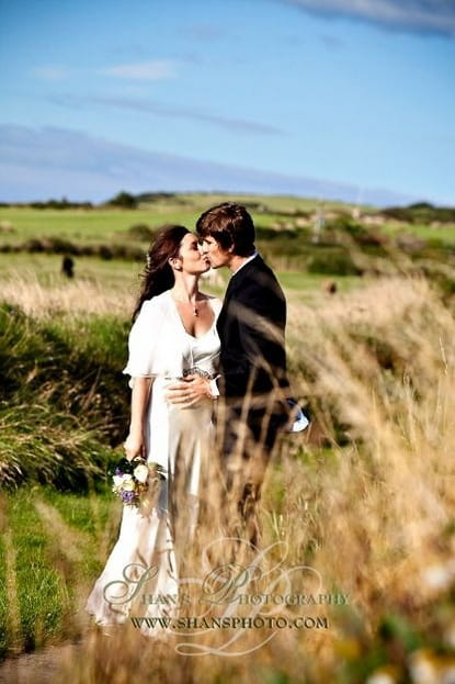 Picture of a bride and groom kissing in a field by Shan Fisher Photography on the Isle of Man