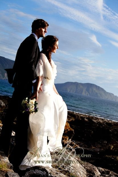 Picture of a bride and groom standing on some rocks by Shan Fisher Photography on the Isle of Man
