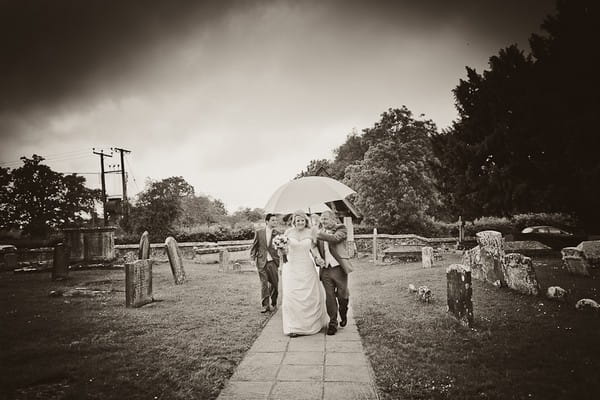 Bride walking to church under an umbrella - Martins Kikulis Photography