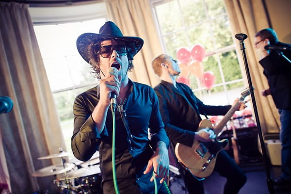 Wedding guest in cowboy hat singing with band - Martins Kikulis Photography