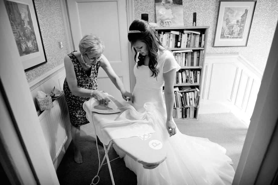 Bride having her wedding dress ironed by Martin Beddall Photography