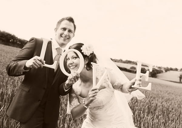 Bride and groom holding up LOVE letters - Picture by Rebecca Wedding Photography