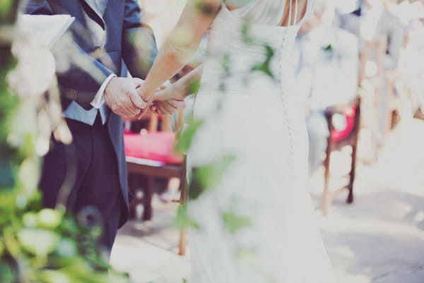 Closeup of bride and groom holding hands