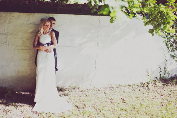 Bride and groom standing by a wall