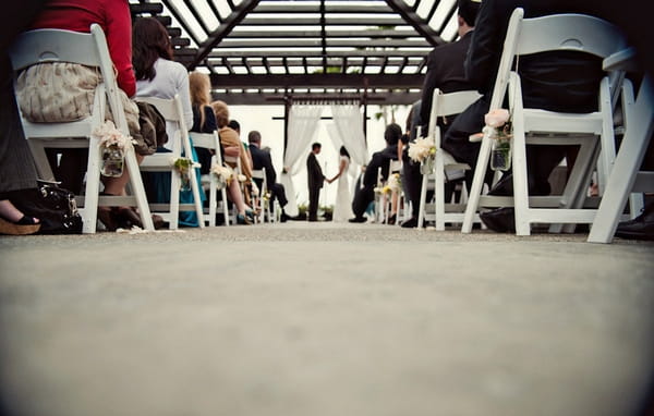 Wedding ceremony viewed through rows of chairs - Picture by Captured by Aimee