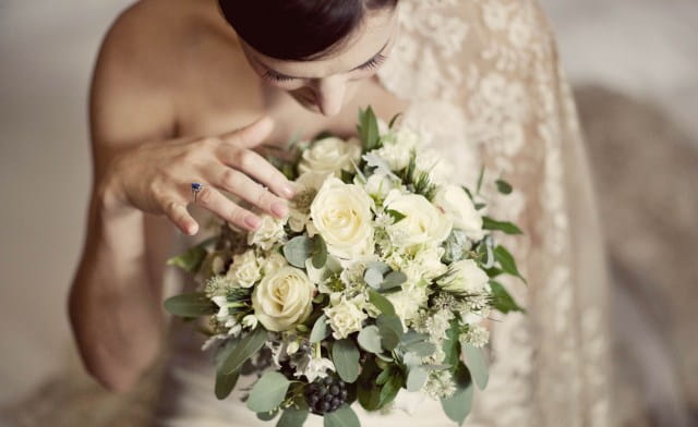 Bride looking at bouquet - Picture by Laura McCluskey Photography