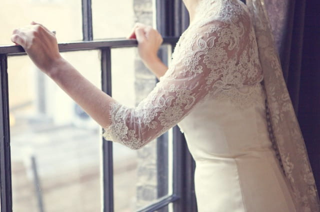 Bride standing at window - Picture by Laura McCluskey Photography