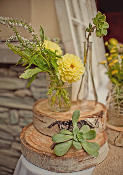 Yellow flowers in vase on a log - Picture by Captured by Aimee