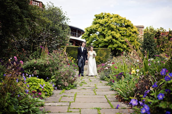 Bride and groom walking through garden - Picture by Andrew J R Squires Photography