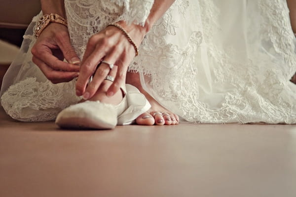 Bride putting on ballet shoes - Picture by Captured by Aimee