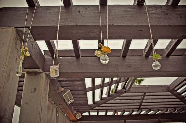 Small vases of flowers hanging from beam - Picture by Captured by Aimee