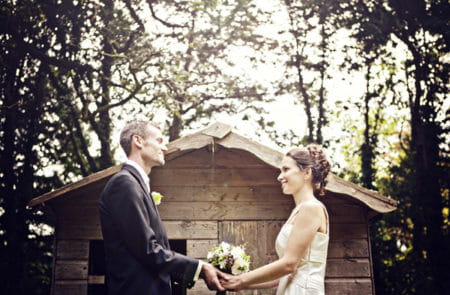 Bride and groom holding hands facing each other outside a shed - Picture by Andrew J R Squires Photography