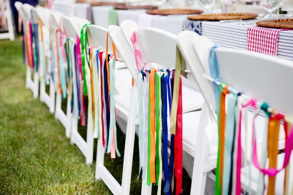 Colourful ribbons hanging from wedding chairs - Picture by Laura Ivanova Photography