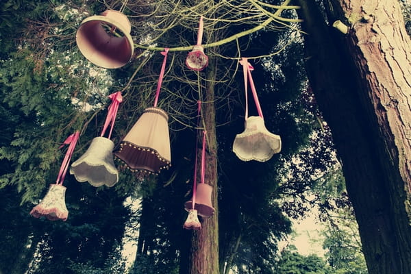 Lamp shades hanging from trees - Picture by Ian Shoots Weddings