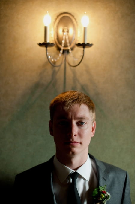 Groom standing in front of wall light - Picture by Rojo Foto Design