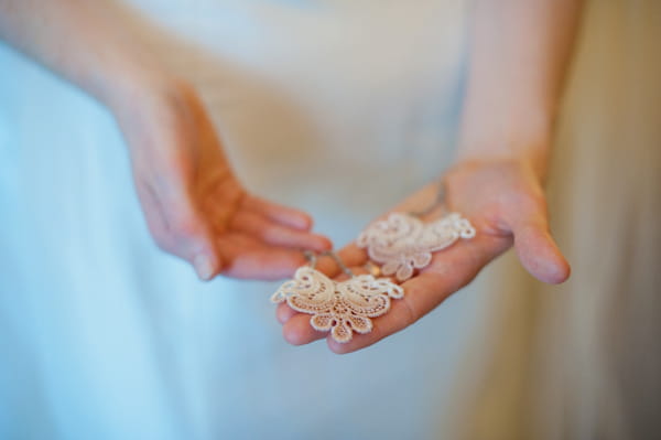 Bride holding earrings in hand - Picture by Rojo Foto Design