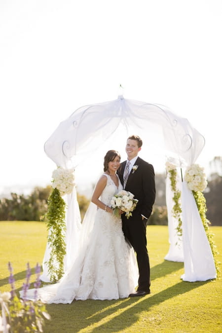 Bride and groom posing by arch - Picture by Allyson Magda Photography