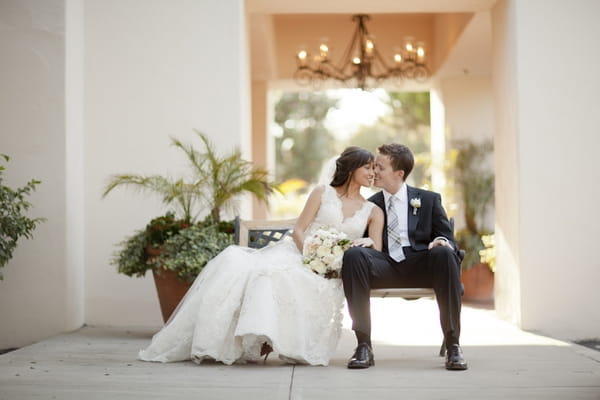 Bride and groom sitting on bench - Picture by Allyson Magda Photography