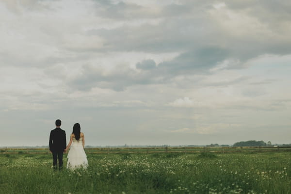 Back of bride and groom standing in field - Picture by Jonas Peterson Photography