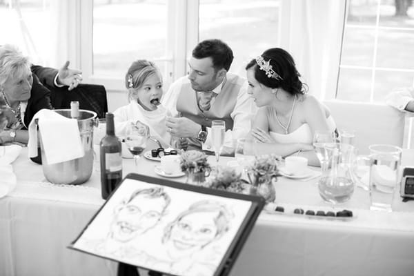 Bride and groom sitting in front of caricature - Picture by Hayley Ruth Photography