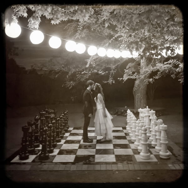 Bride and groom kissing on giant chess board - Picture by Jonas Peterson Photography