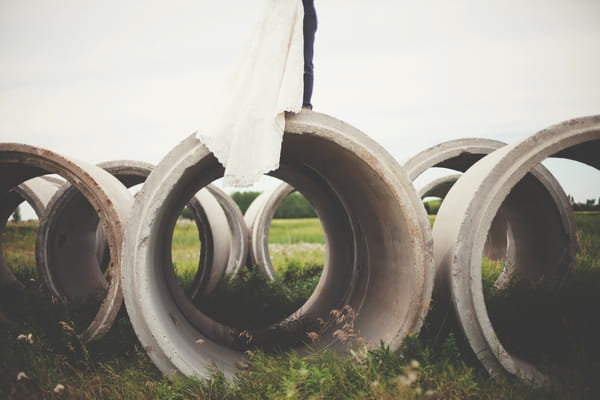 Bride and groom standing on top of concrete cylinder - Picture by Josh Dookhie Photography