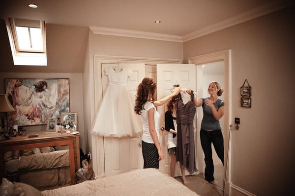 Bride handing bridesmaid her dress - Picture by Archibald Photography
