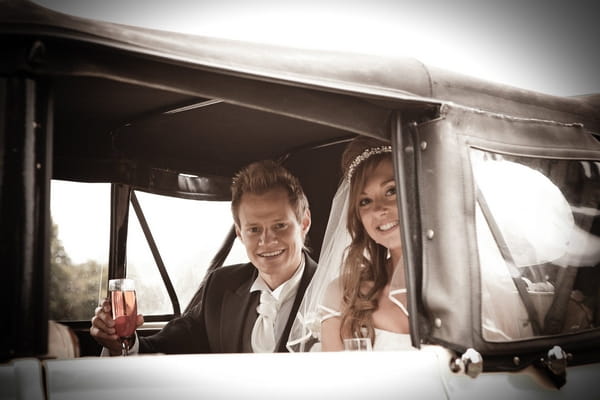 Bride and groom in back of wedding car - Picture by Archibald Photography