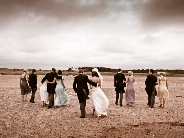 Wedding party walking across beach - Picture by Archibald Photography