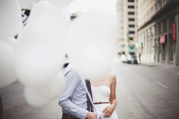 Bride and groom with faces hidden by balloons - Picture by Josh Dookhie Photography