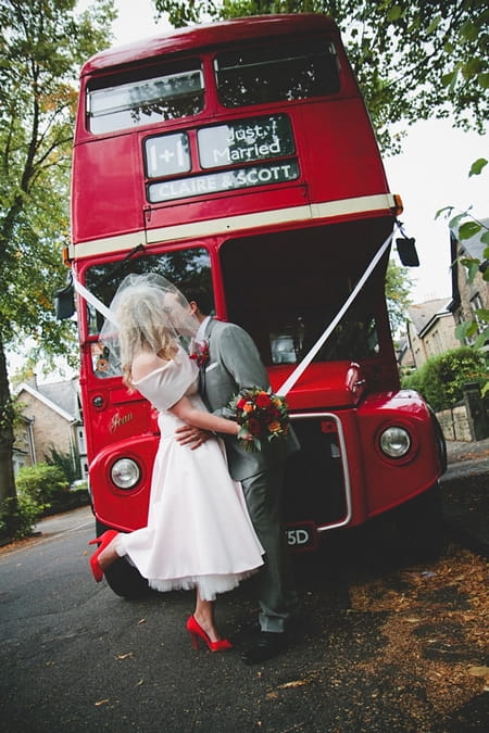 Bride and groom kissing in front of red wedding bus - Picture by McKinley-Rodgers Photography