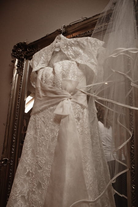 Front of lace wedding dress hanging on mirror - Picture by Archibald Photography