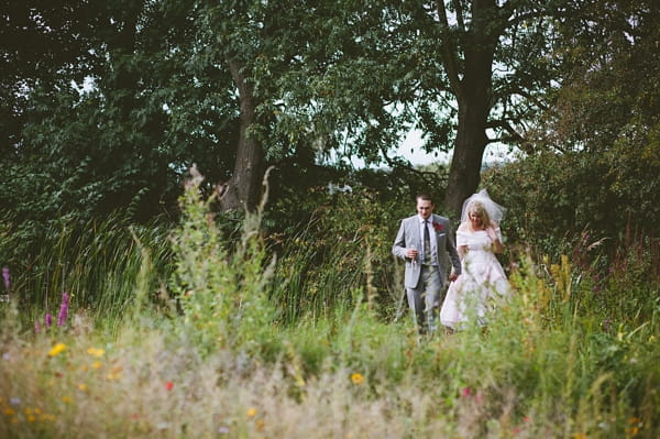 Bride and groom walking through field - Picture by McKinley-Rodgers Photography