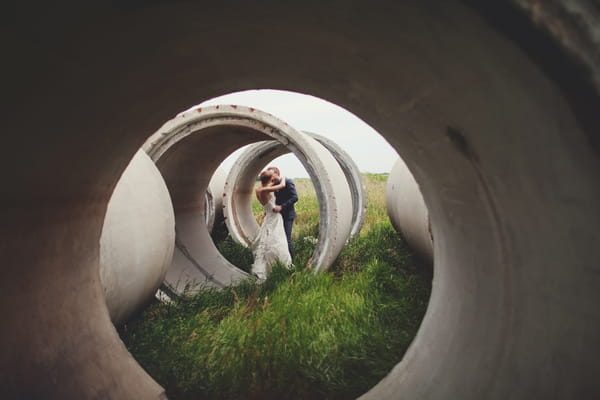 Bride and groom kissing behind concrete cylinders - Picture by Josh Dookhie Photography