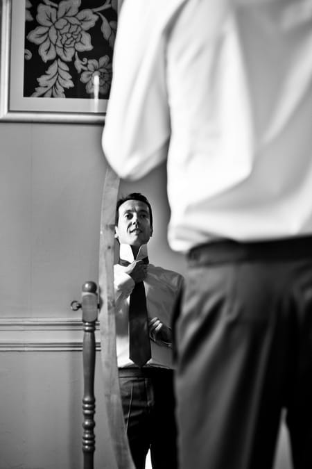 Groom adjusting tie in mirror - Picture by Anneli Marinovich Photography