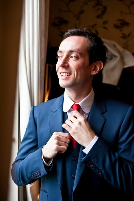 Groom doing up red tie - Picture by Anneli Marinovich Photography