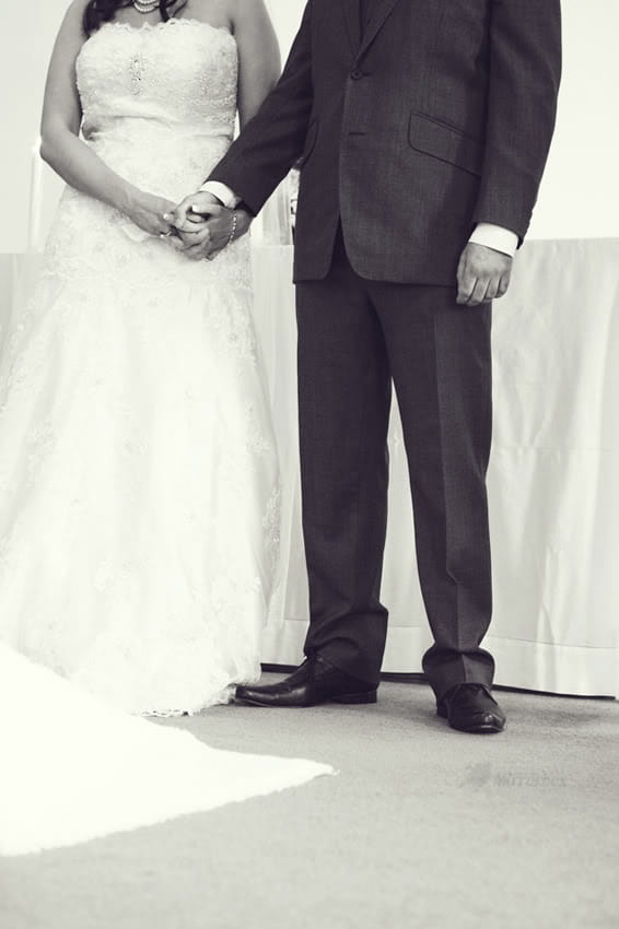 Bride and groom holding hands in church - Picture by Mirrorbox Photography