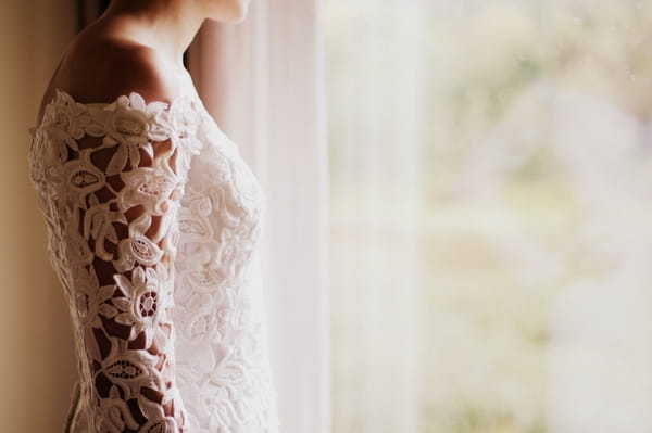 Bride in lace wedding dress standing by the window - Picture by Judy Pak Photography