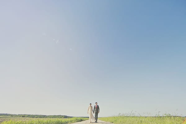 Bride and groom holding hands with vast landscape behind them - Picture by Our Labor of Love Photography