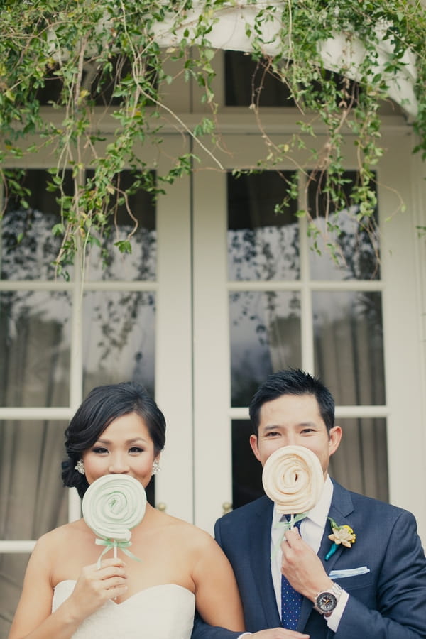 Bride and groom holding lollipops - Picture by onelove photography