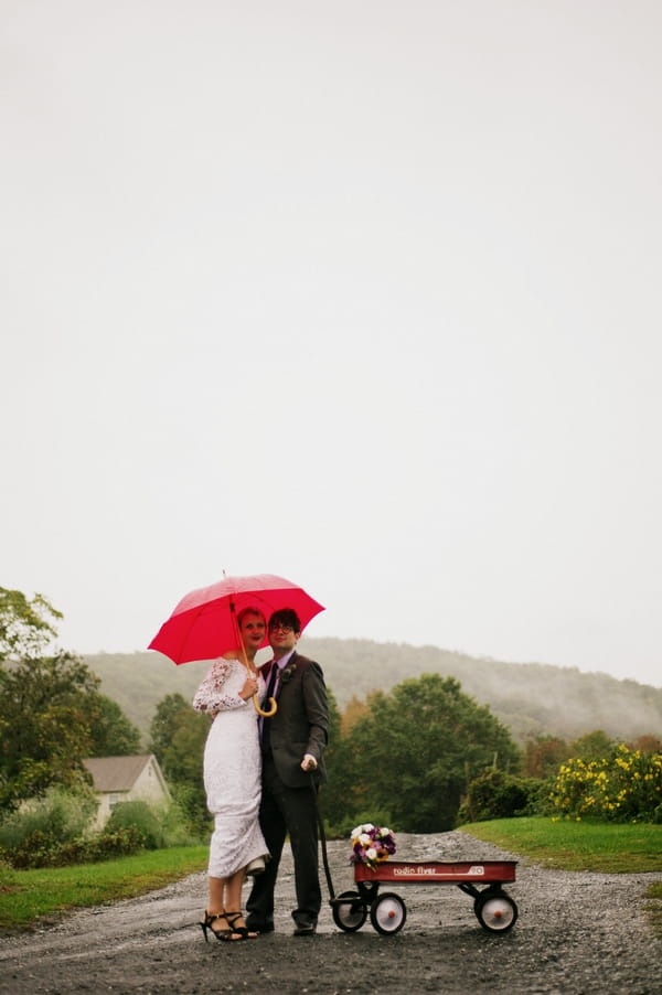Bride and groom under red umbrella in the rain - Picture by Judy Pak Photography