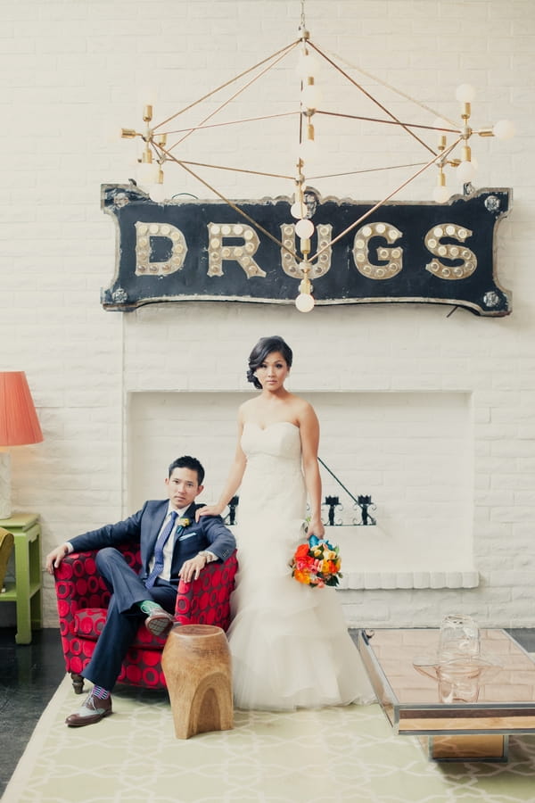 Bride and groom in front of a sign saying drugs - Picture by onelove photography