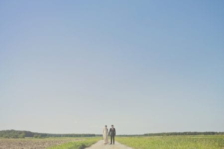 Bride and groom standing on a long path with vast landscape in background - Picture by Our Labor of Love Photography