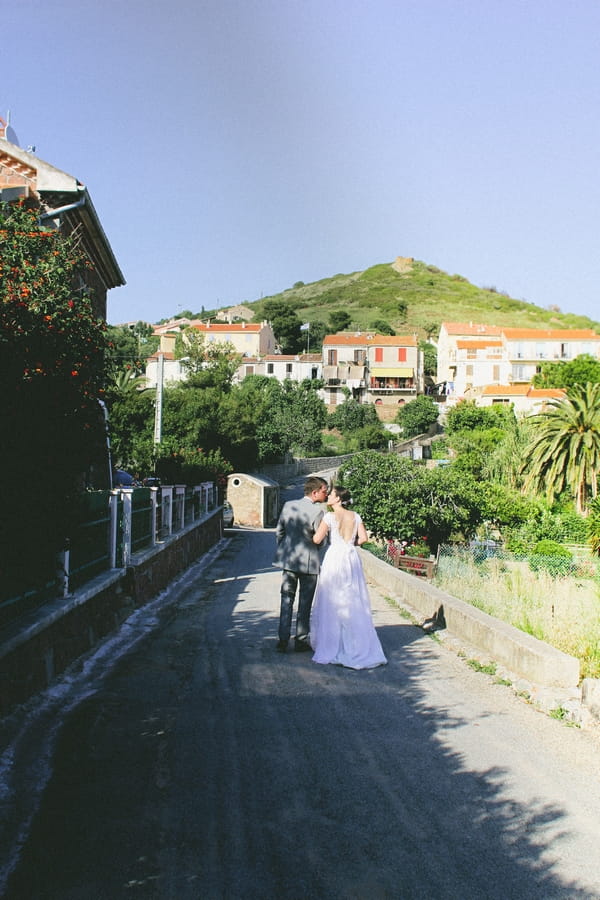 Back of bride and groom walking through streets of Cargese - Picture by DanielRM
