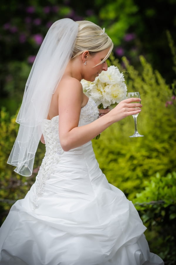 Bride carrying bouquet and glass of Champagne - Picture by Pixies in the Cellar