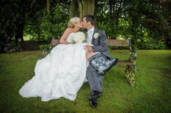 Groom kissing bride in wellies on bench - Picture by Pixies in the Cellar