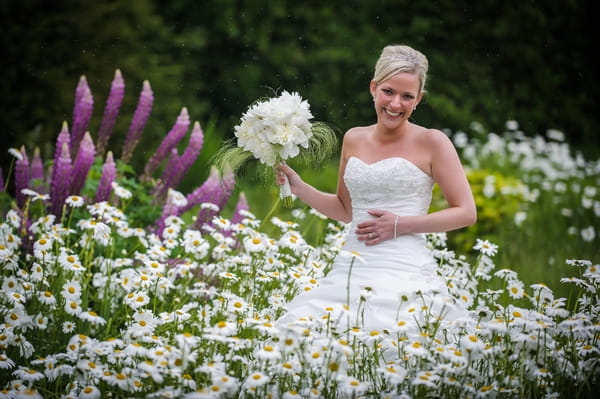 Bride holding bouquet in field of flowers - Picture by Pixies in the Cellar