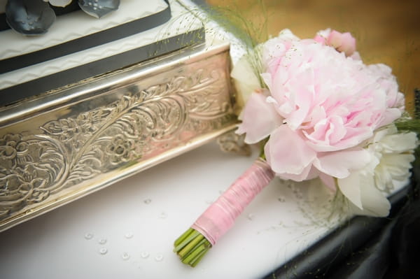 Pink wedding bouquet next to wedding cake - Picture by Pixies in the Cellar